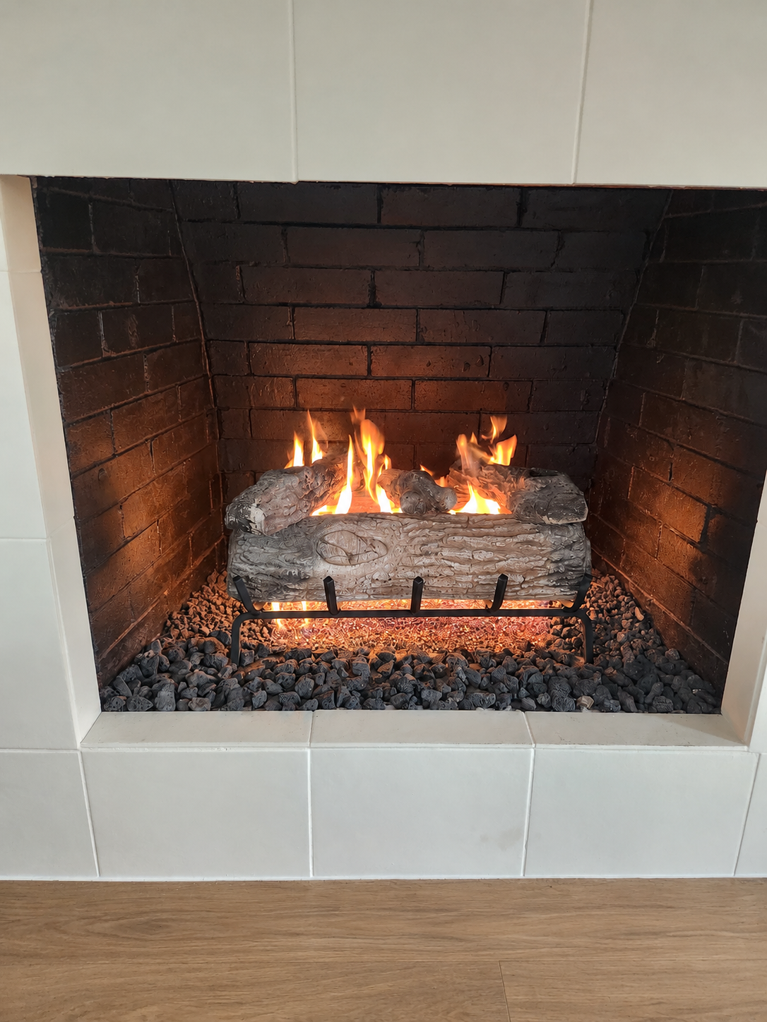 Gas log fireplace with white surround and visible gas logs
