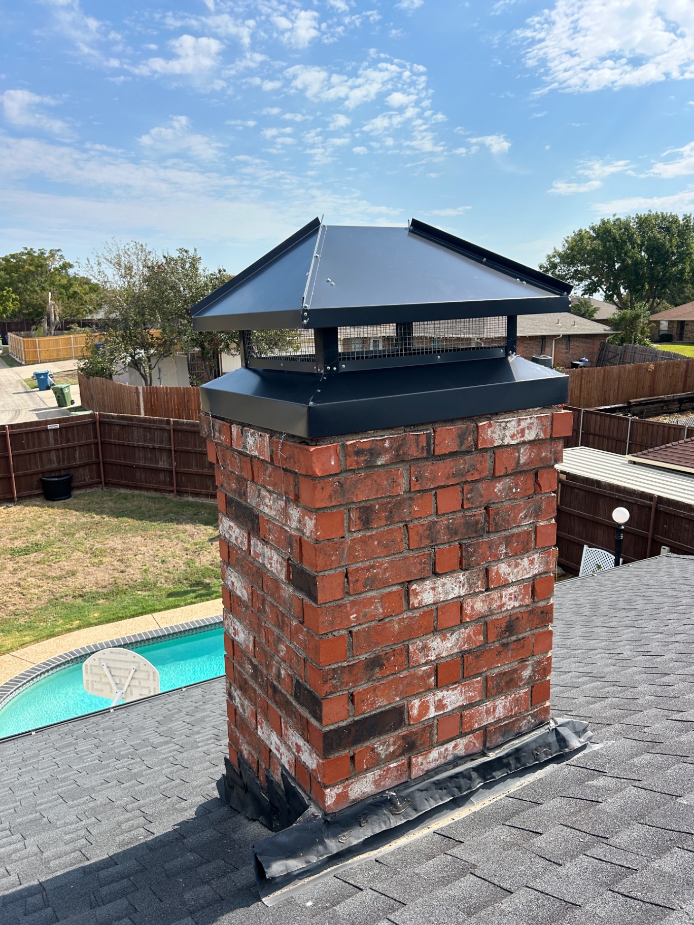 Completed exterior chimney with a large black custom cap